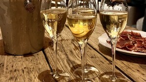 A wooden table with three wine glasses and a bottle of champagne.