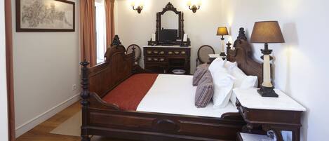 Un dormitorio ordenado con una cama de madera, un aparador, un espejo y dos apliques.