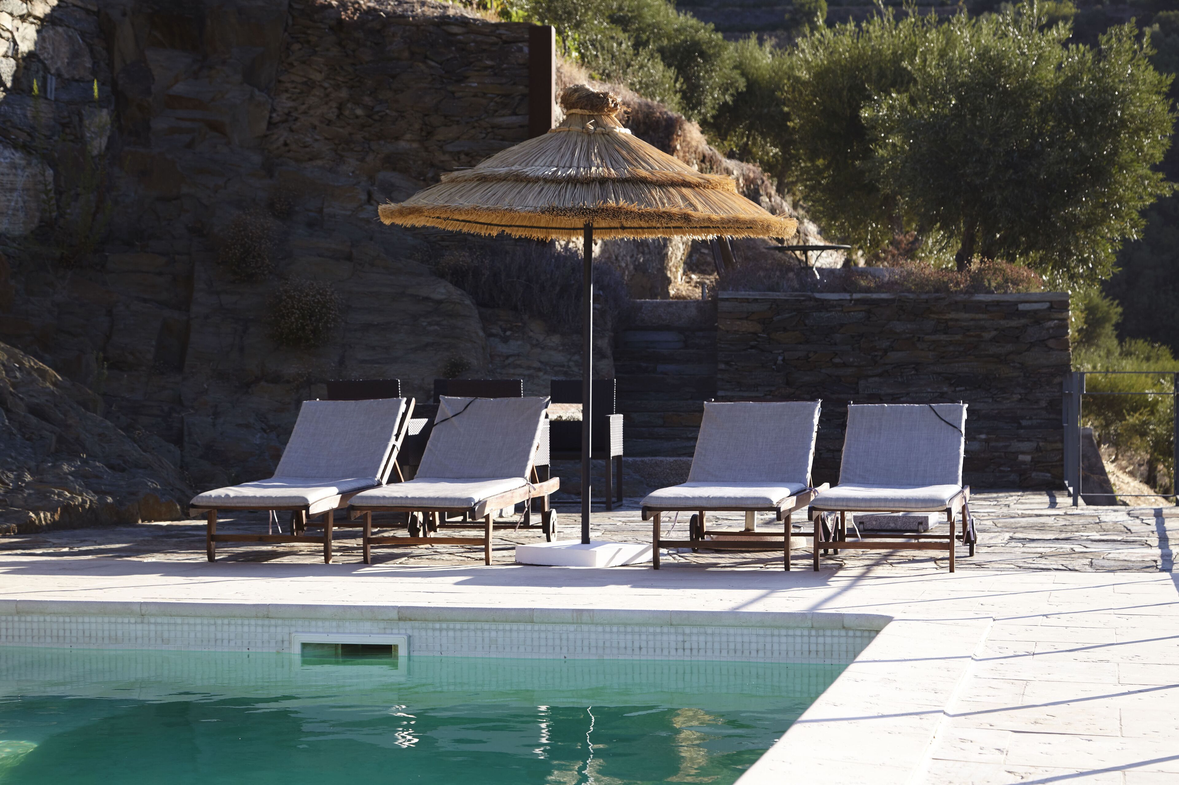 A poolside area with lounge chairs and a thatched umbrella.