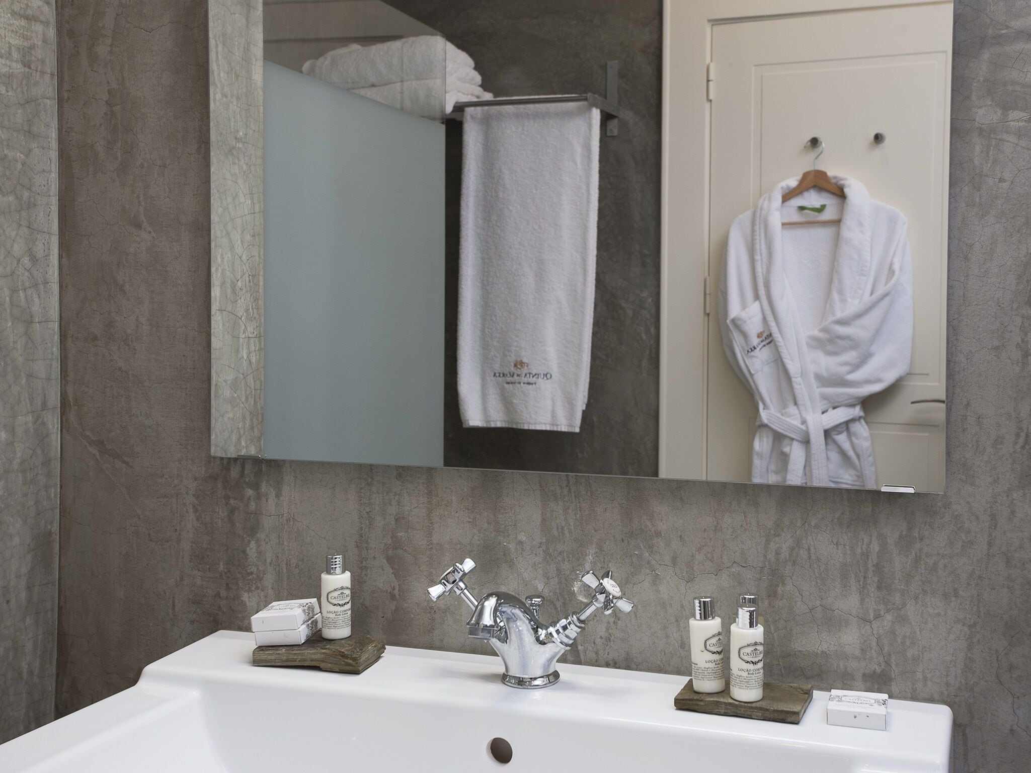 A bathroom with a large mirror, a sink with a modern faucet, and toiletries on the counter.