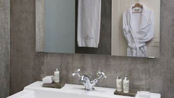 A bathroom with a large mirror, a sink with a modern faucet, and toiletries on the counter.