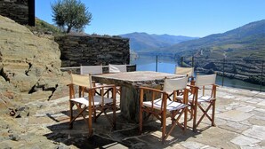 Una mesa de piedra con seis sillas, con vistas a un río y montañas.