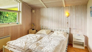 A bedroom with a bed, bedside table, lamp, and window with a view of greenery. - 5 Person Holiday Home in Nakskov (Nakskov)