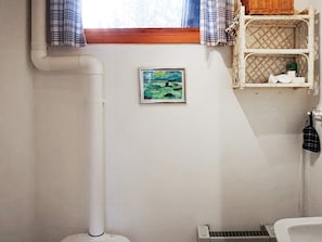 A bathroom with a window, a framed painting, a radiator, and a shelf with toiletries. - 6 Person Holiday Home in Blido (Blidö)
