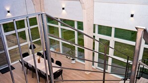 A modern interior with a staircase, large windows, and a dining area with a table and chairs.