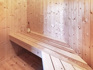 A wooden sauna with a bench and a bottle of oil. - 5 Star Holiday Home in Dannemare (Dannemare)