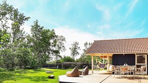 A patio area with outdoor furniture, a hammock, and a dining table. - 5 Star Holiday Home in Dannemare (Dannemare)