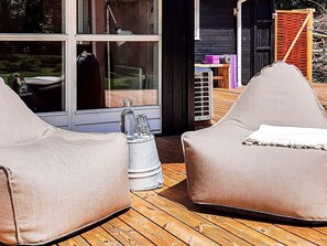 Two beige bean bag chairs on a wooden deck with a glass door leading to an interior space. - 5 Star Holiday Home in Dannemare (Dannemare)