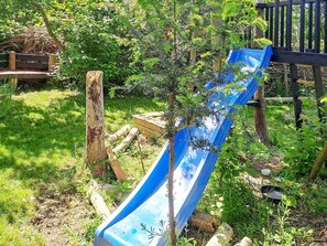 A blue slide in a grassy area with trees and wooden structures. - 5 Star Holiday Home in Dannemare (Dannemare)