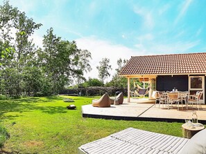 A patio area with outdoor furniture, a hammock, and a dining table. - 5 Star Holiday Home in Dannemare (Dannemare)