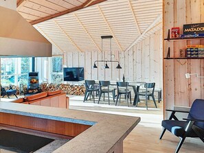 A modern interior with a wooden ceiling, a fireplace, a dining area, and a television. - 5 Star Holiday Home in Dannemare (Dannemare)