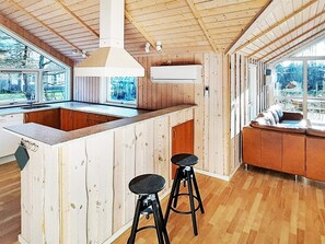 A kitchen with wooden walls, a central island, and two stools. - 5 Star Holiday Home in Dannemare (Dannemare)