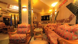 Een hotel lobby met een zithoek, stoelen, een kleine tafel en een televisie.