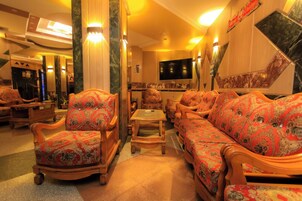 Eine Hotelhalle mit einer Sitzecke, Stühlen, einem kleinen Tisch und einem Fernseher.