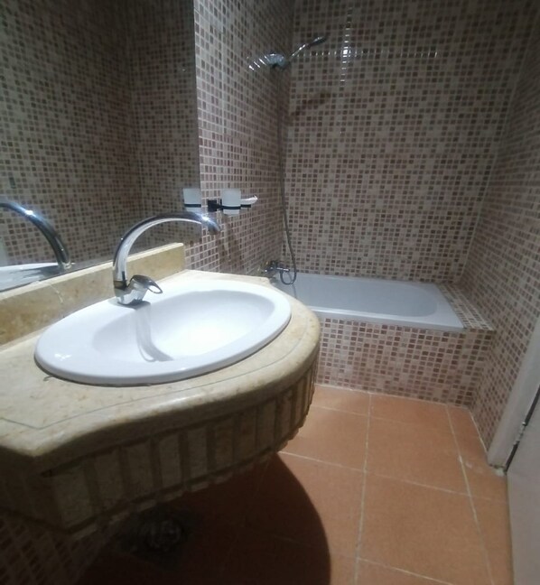 Un baño con lavamanos, espejo y zona de ducha.