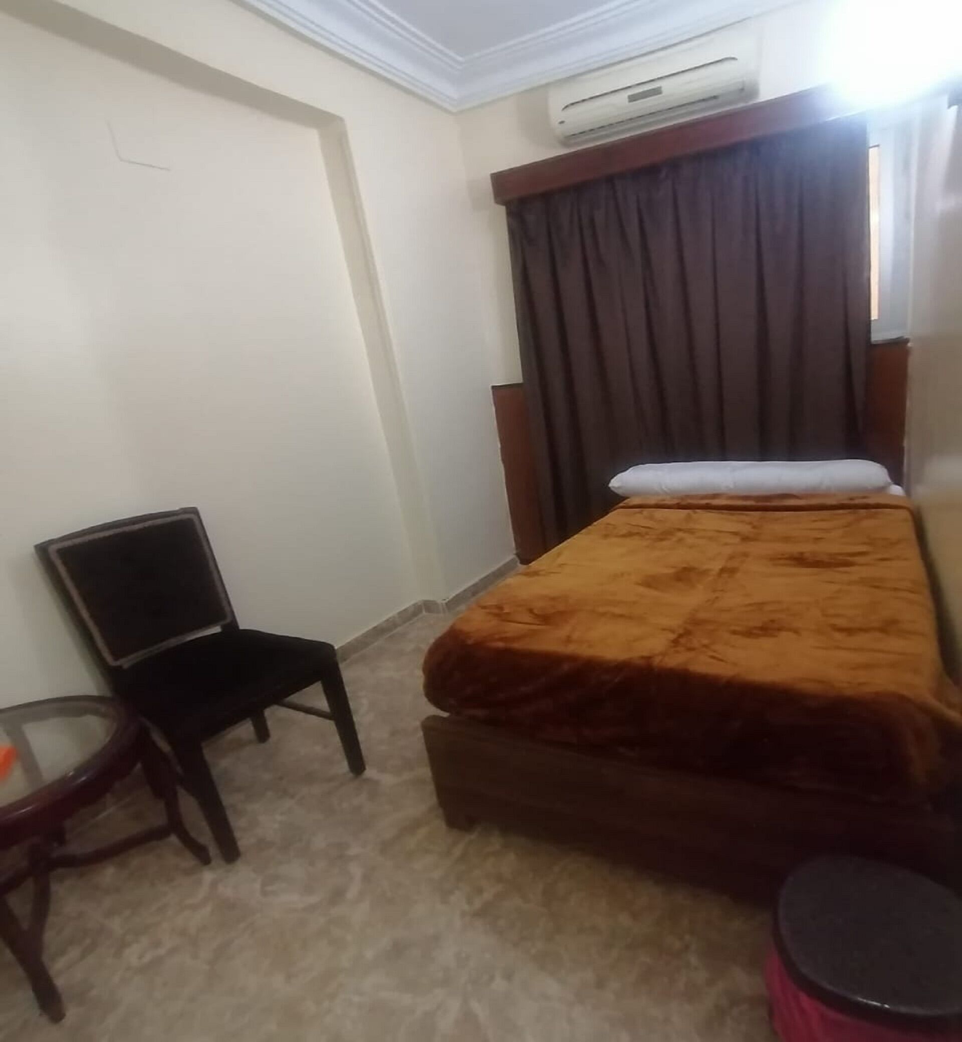 A small, neatly arranged room with a bed, a chair, and a small table.