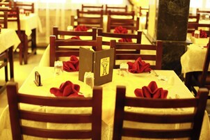 Un restaurant où les tables sont dressées pour le service, avec des serviettes rouges et un présentoir à menus.