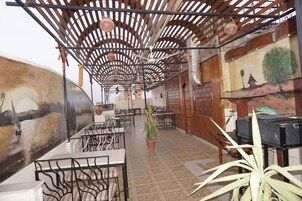 Ein geräumiges Restaurant mit hohen Holzbalkendecken, einem Wandgemälde an der linken Wand und einer Topfpflanze in der Mitte.