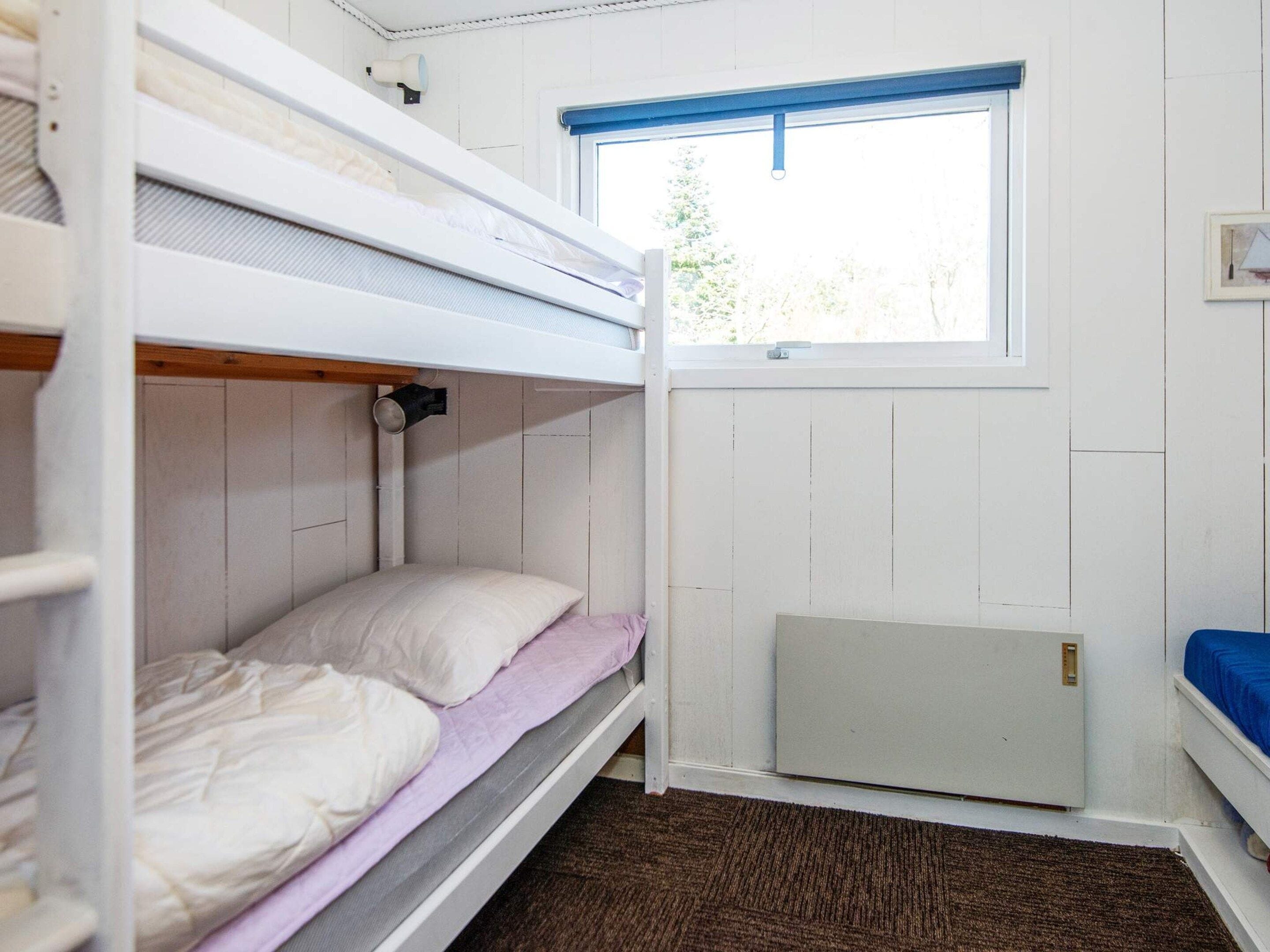 Une chambre avec un lit superposé, une fenêtre, un radiateur et une porte.