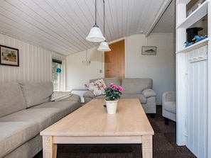 A living room with two sofas, a wooden coffee table, and a white cabinet with decorative items.