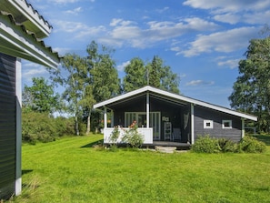 A single-story house with a porch, surrounded by a well-maintained lawn and trees.