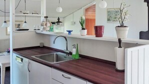 A modern kitchen with a stainless steel sink, white cabinetry, and a wooden countertop.