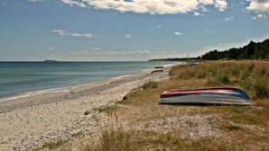 A beach with boats, a clear sky, and a distant island.
