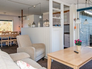 Een gezellige woonkamer met een bank, een houten tafel en een eethoek met een tafel en stoelen.