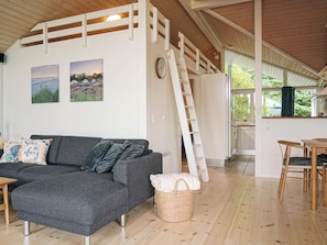 A modern interior with a grey sofa, a woven basket, and a wooden ladder.