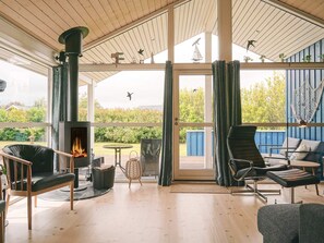A cozy room with a fireplace, comfortable seating, and a view of the garden. - 4 Star Holiday Home in Nexo (Nexø)
