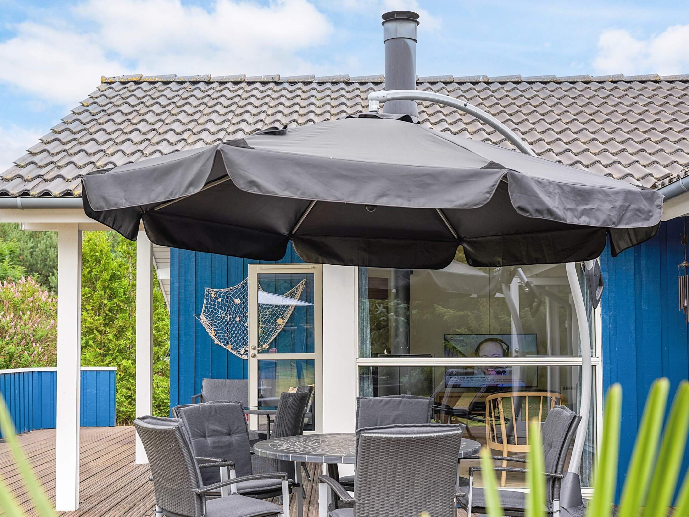 An outdoor patio with a covered seating area, a glass enclosure, and a blue exterior wall.