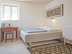 A bedroom with a bed, a desk, a chair, a lamp, a rug, and a wall-mounted light fixture. - 5 Star Holiday Home in Svaneke (Svaneke)
