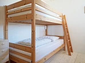 A bunk bed with a wooden frame, a bedside table with drawers, and a ladder. - 5 Star Holiday Home in Svaneke (Svaneke)
