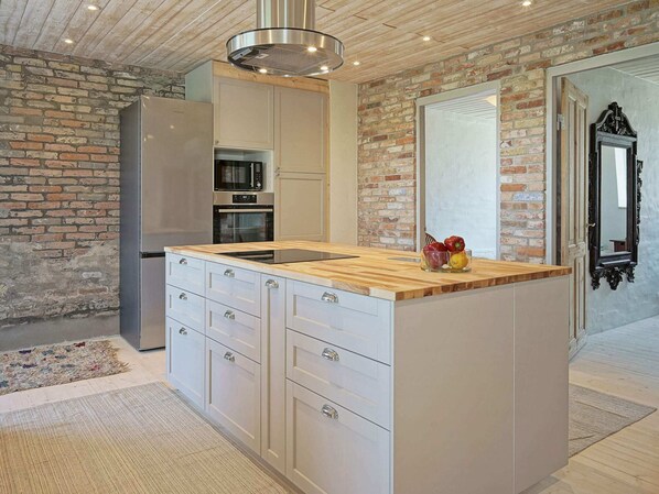 Una cocina moderna con una isla central, electrodomésticos integrados y una pared de ladrillo.