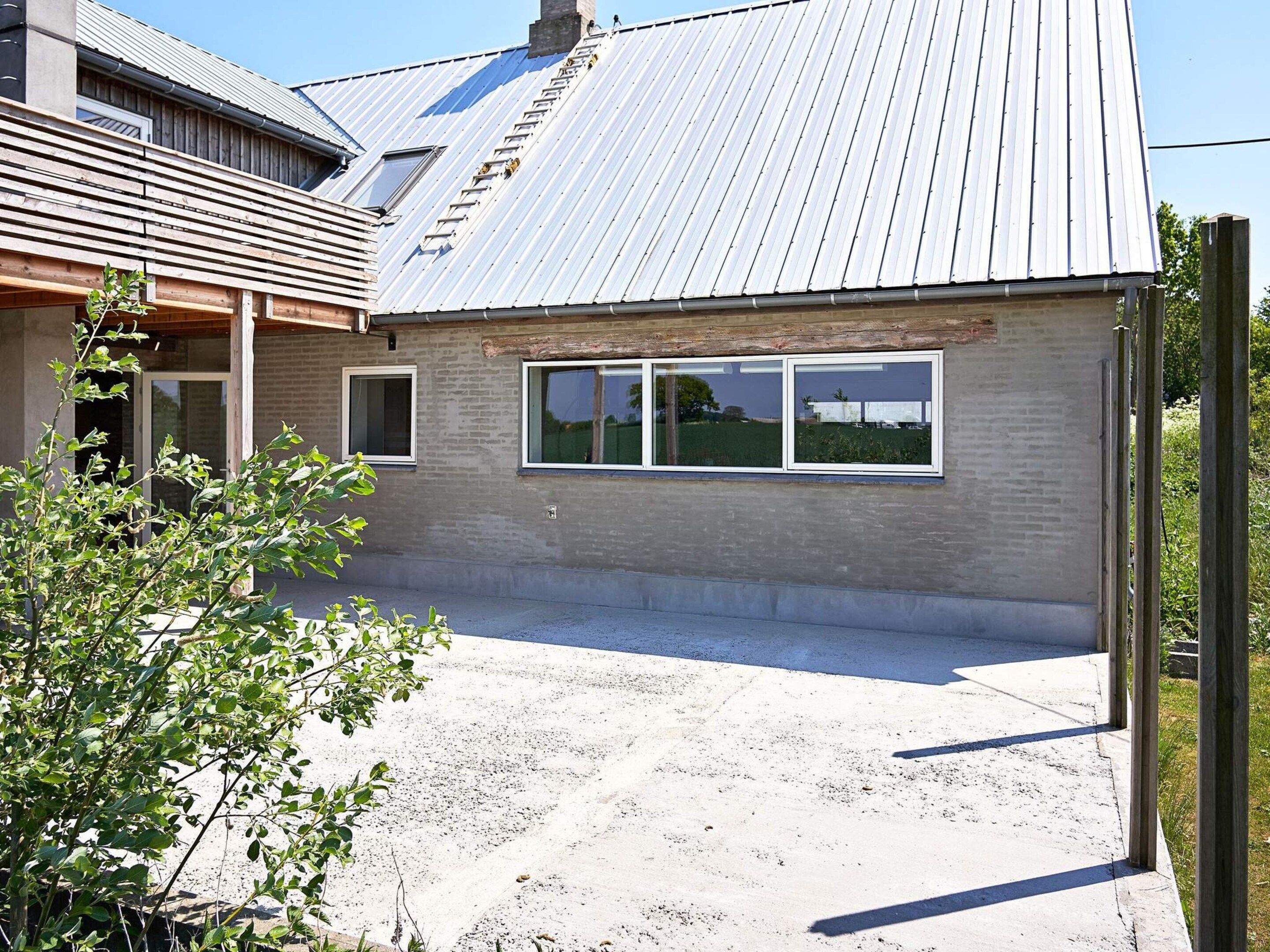 En boligbygning med tagpap, murstensfacade og en belagt indkørsel.