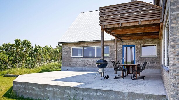A patio area with a barbecue grill, outdoor table, and chairs.
