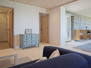 Une pièce avec un plafond en bois, une commode bleue, un canapé et un mur en briques.