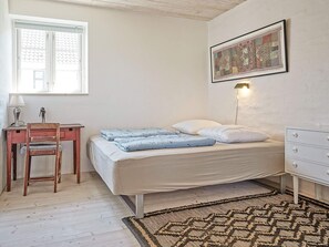 Une chambre à coucher comprenant un lit, un bureau avec une chaise, une lampe, un luminaire fixé au mur et un tapis à motifs.