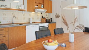 A modern kitchen with wooden cabinets, a Bosch dishwasher, and a dining area with a wooden table and chairs. - 6 Person Holiday Home in Aakirkeby (Akirkeby)