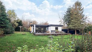 A modern house with a deck, surrounded by a well-maintained lawn and trees.