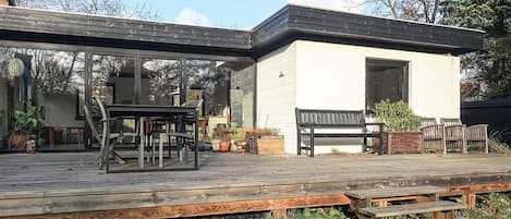 A modern house with a covered patio, a dining area, and a bench.