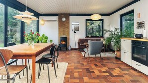 A modern kitchen with a large window, a built-in oven, and a dining area with a wooden table and chairs.