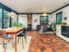 A modern kitchen with a large window, a built-in oven, and a dining area with a wooden table and chairs. - 5 Person Holiday Home in Gilleleje (Gilleleje)