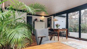 A modern dining area with a wooden table, chairs, and a large potted plant.