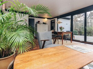 A modern dining area with a wooden table, chairs, and a large potted plant. - 5 Person Holiday Home in Gilleleje (Gilleleje)