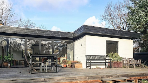A modern house with a covered patio, a dining area, and a bench.