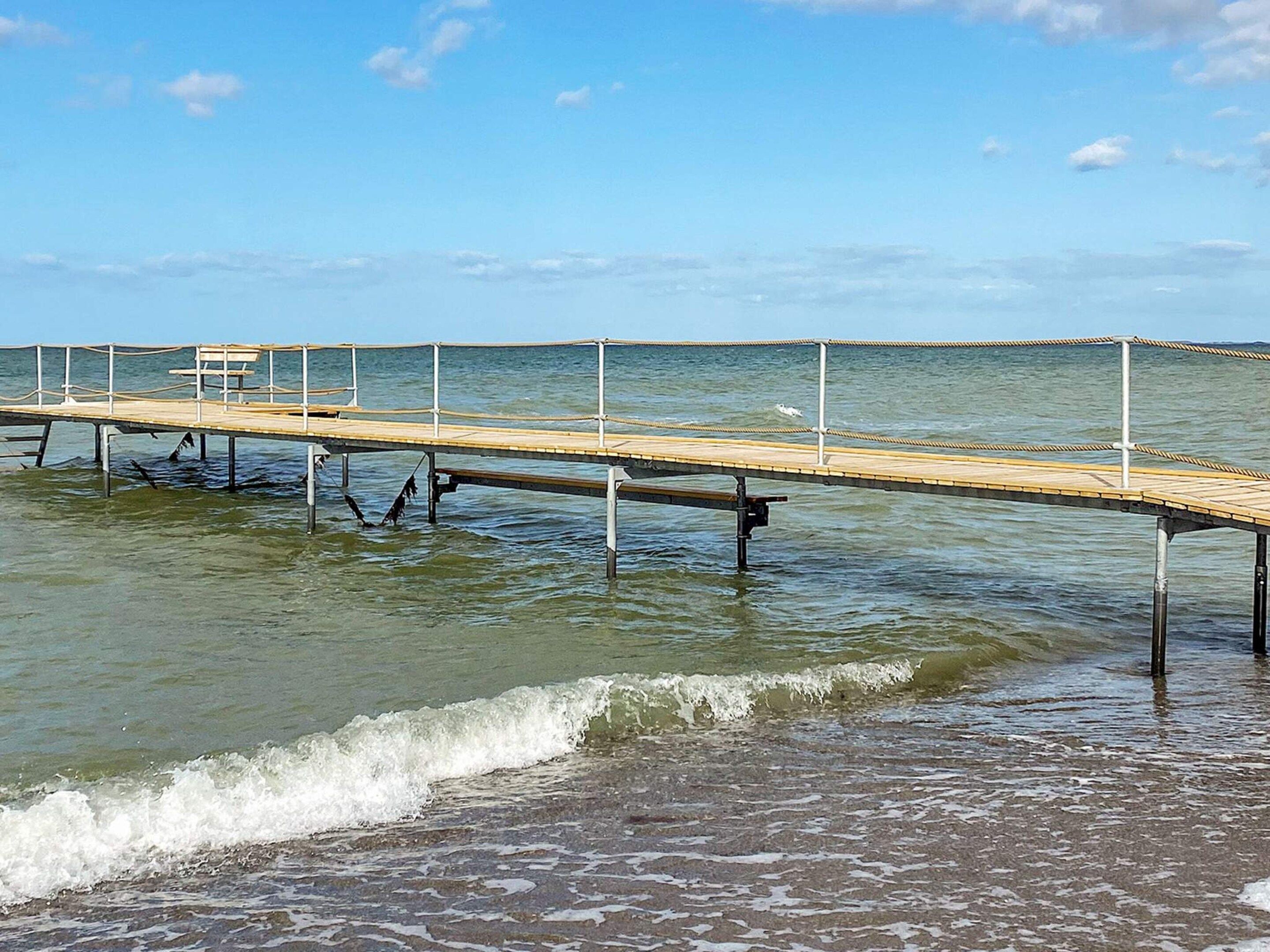 A wooden pier extending into calm water with a clear sky above.