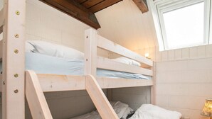 A bunk bed room with a wooden ladder, a bedside table with a lamp, and a window. - 5 Person Holiday Home in Otterup (Otterup)