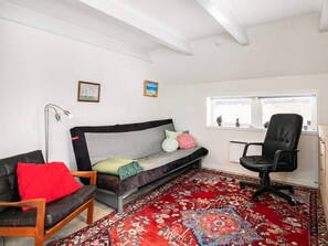 A room with a sofa, a chair, a desk, a window, and a patterned rug. - 5 Person Holiday Home in Otterup (Otterup)