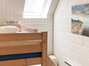 A room with a bunk bed, a skylight, a white brick wall, and a painting of a beach scene. - 5 Person Holiday Home in Otterup (Otterup)